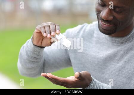 Close up of black man using hand sanitizer rub standing in a park Stock Photo