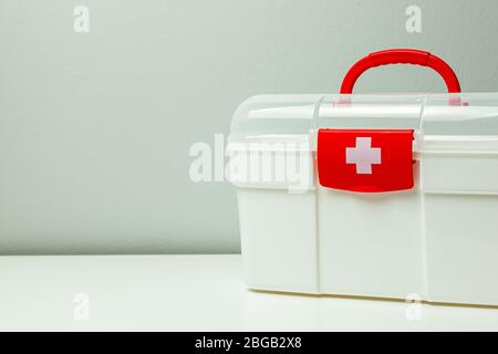 First Aid Kit. White box with a cross and a red clasp on a gray background. Stock Photo