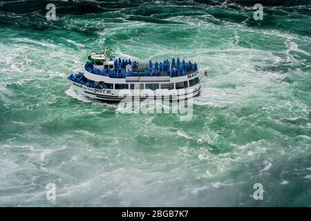 Niagara Falls, NY, USA - June 13, 2019: Ship with tourists moves to Niagara falls, Falls boat tour experience is North America oldest attraction, and Stock Photo