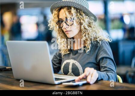 Beautiful young woman working with roaming phone device like digital travel nomad or smart work at the bar cafe - modern people and technology new job Stock Photo