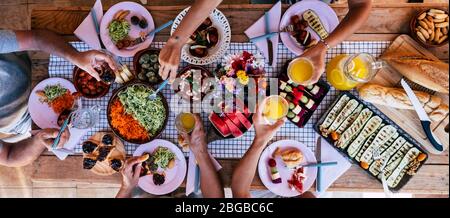 Top vertical view of table full of food and drinks and happy people friends celebrating and. enjoy together eating and having fun - concept of social Stock Photo