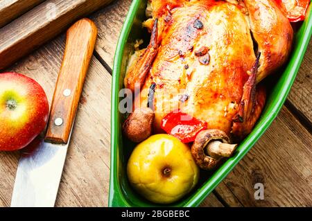 Baked chicken with apples on old wooden table.Fried chicken with apples.Roasted chicken with apples in baking dish Stock Photo