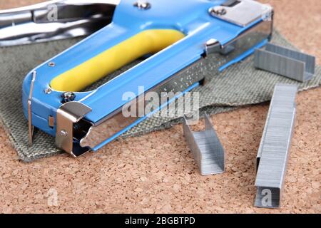 Construction stapler and staples on cork board close up Stock Photo