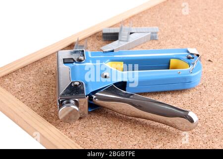 Construction stapler and staples on cork board close up Stock Photo