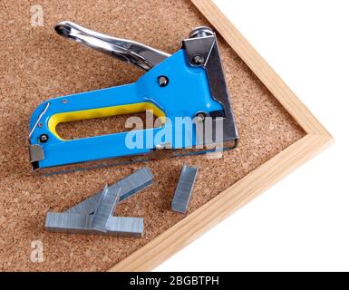 Construction stapler and staples on cork board close up Stock Photo