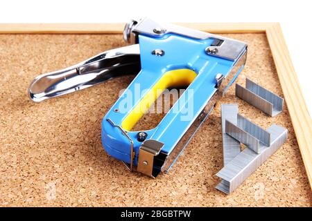 Construction stapler and staples on cork board close up Stock Photo