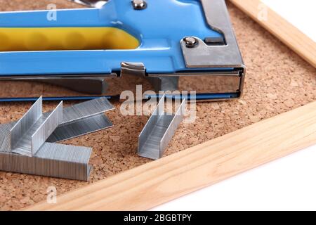 Construction stapler and staples on cork board close up Stock Photo