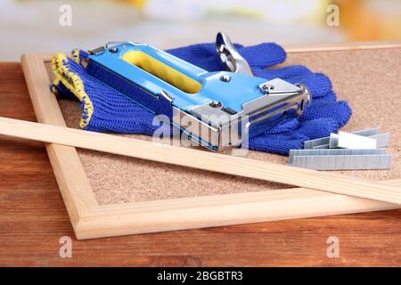Construction stapler with gloves and staples on cork board close up Stock Photo