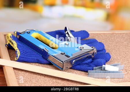 Construction stapler with gloves and staples on cork board close up Stock Photo