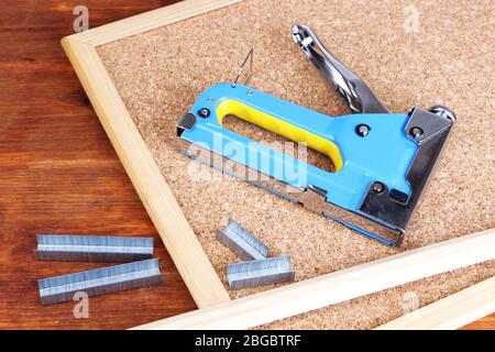 Construction stapler and staples on cork board close up Stock Photo