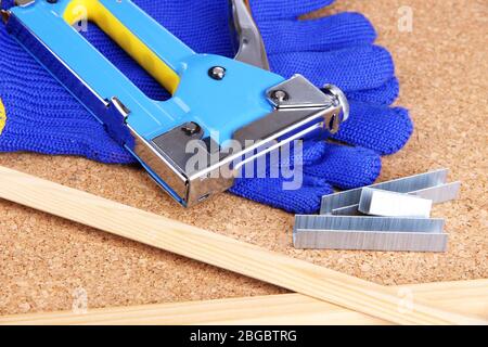 Construction stapler with gloves and staples on cork board close up Stock Photo