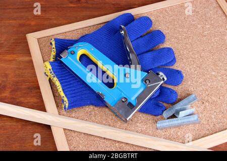 Construction stapler with gloves and staples on cork board close up Stock Photo