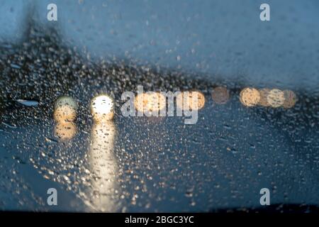Blurred view. Raindrops on the car windshield at night. Cars are coming towards us, you can see the light from the headlights Stock Photo