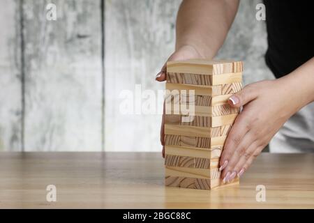 Girl hand putting wooden bricks on a table. Tower construction game. Stock Photo
