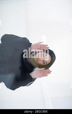 young arabian muslim woman in traditional hijab clothes praying on the glass floor before iftar dinner during a ramadan feast at home Stock Photo