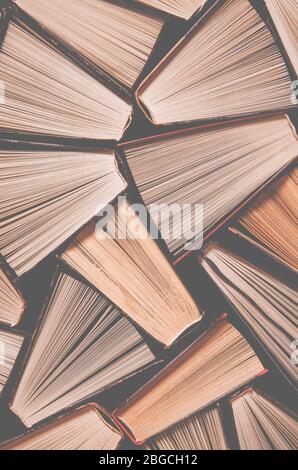 Many old multi-colored open books stand on the bookshelf in the library Stock Photo