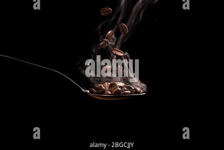 Spoon with coffee beans and steam on black background Stock Photo