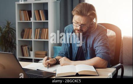 Man looking book making notes Stock Photo