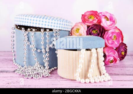 Decorative boxes with beads and flowers on table on bright background Stock Photo
