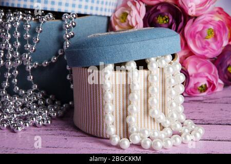 Decorative boxes with beads and flowers on wooden background Stock Photo