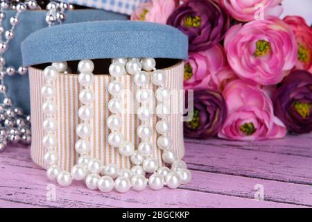 Decorative boxes with beads and flowers on wooden background Stock Photo