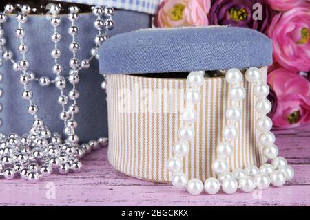 Decorative boxes with beads and flowers on wooden background Stock Photo