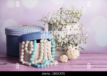 Decorative boxes with beads and flowers on table on bright background Stock Photo