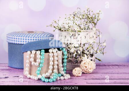 Decorative boxes with beads and flowers on table on bright background Stock Photo