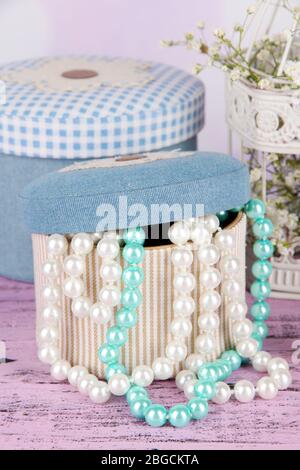 Decorative boxes with beads and flowers on table on bright background Stock Photo