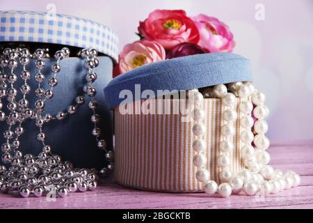 Decorative boxes with beads and flowers on table on bright background Stock Photo