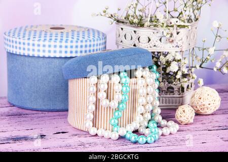 Decorative boxes with beads and flowers on table on bright background Stock Photo