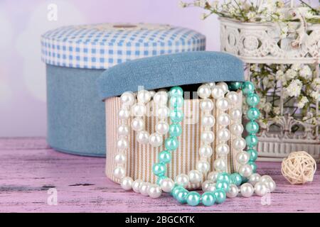 Decorative boxes with beads and flowers on table on bright background Stock Photo
