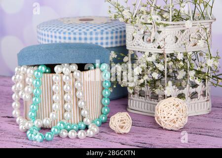 Decorative boxes with beads and flowers on table on bright background Stock Photo