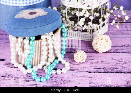Decorative boxes with beads and flowers on wooden background Stock Photo