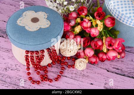 Decorative boxes with beads and flowers on wooden background Stock Photo