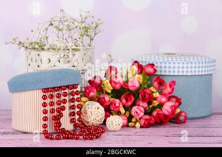 Decorative boxes with beads and flowers on table on bright background Stock Photo