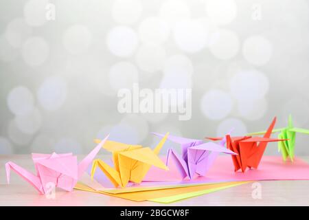 Origami cranes on wooden table, on light background Stock Photo