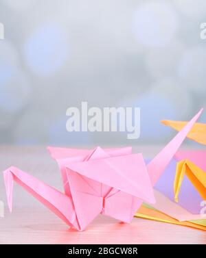 Origami cranes on wooden table, on light background Stock Photo