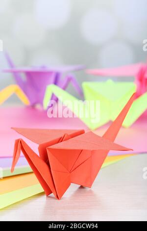 Origami cranes on wooden table, on light background Stock Photo