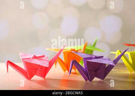 Origami cranes on wooden table, on light background Stock Photo