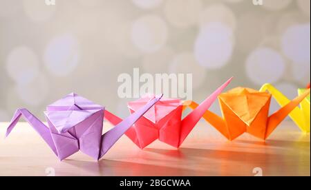 Origami cranes on wooden table, on light background Stock Photo