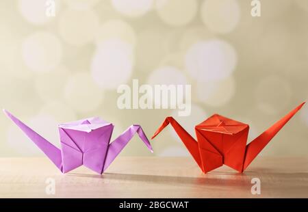 Origami cranes on wooden table, on light background Stock Photo