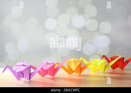 Origami cranes on wooden table, on light background Stock Photo