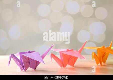 Origami cranes on wooden table, on light background Stock Photo