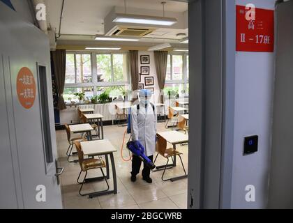 Beijing, China. 21st Apr, 2020. A staff member disinfects a classroom at Beijing National Day School in Beijing, capital of China, April 21, 2020. Recently, Beijing National Day School has carried out a comprehensive disinfection and sterilization operation on the campus, and has set up intelligent temperature measuring doors, intelligent hands disinfection devices in key areas of the campus to ensure the safe and orderly return of teachers and students. Credit: Ren Chao/Xinhua/Alamy Live News Stock Photo