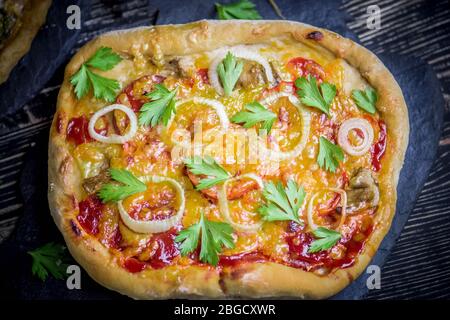 Mixed pizza with chicken, pepper, olives, onion, basil on pizza board. Close up view of baked homemade piza. Rustic pizza home made food. Stock Photo