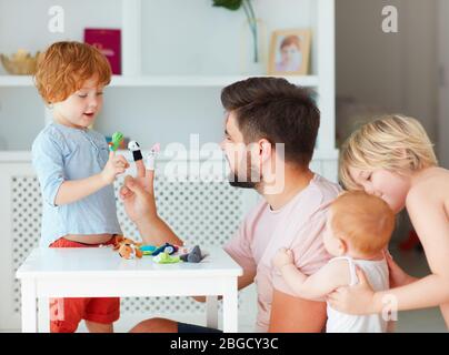 happy father playing with kids at home, funny puppet games Stock Photo