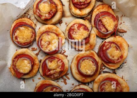 Small pizzas on baking paper close up Stock Photo