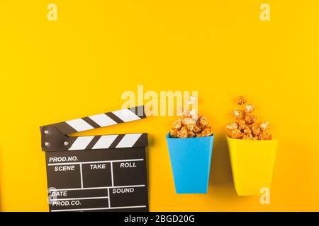 Popcorn and clapperboard on yellow background. Top view Stock Photo