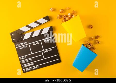 Popcorn and clapperboard on yellow background. Top view Stock Photo